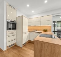 A kitchen in a 3-room apartment with a wooden decor floor and white cabinets.