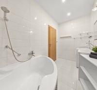 Bathroom with a bathtub, white tiles, a sink, and wooden doors in a 3-room apartment.