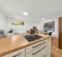 A room with a wooden decor floor, office equipment, and a view of greenery.