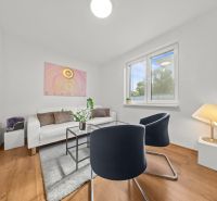 Living room in a 3-room apartment with a wooden decor floor, modern armchairs, and decorations.