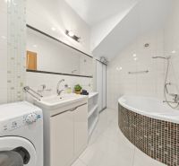 A bathroom with a bathtub in a 3-room apartment complemented by a washing machine and a sink.