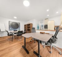 An office with desks, chairs, and a floor with a wood decor in a 3-room apartment.