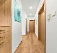 A bright hallway with a wood-patterned floor and wooden doors in a three-room apartment.