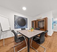 Part of a 3-room apartment with a table, chairs, wooden decor, and artwork on the wall.