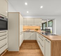 A kitchen with modern white cabinets, wooden floor decor, and a dining nook.