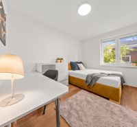 A bright room in a 3-room apartment with a bed, a table, and a wooden-decor floor.