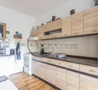 A kitchen in a 3-room apartment with a wooden floor decor and light cabinets.