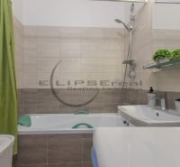 Bathroom in a 3-room apartment with a bathtub, green curtain, and wooden decor tiles.