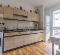 A kitchen with a wooden decor floor and furniture in a 3-room apartment.