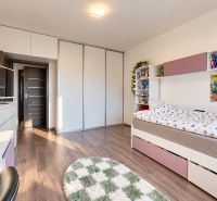 Children's room in a family house with a wooden decor floor and storage spaces.