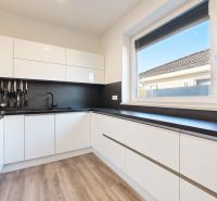 A kitchen in a family house with black appliances and a wood-patterned floor.