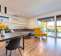 Living room in a family house with seating, a yellow armchair, and a wooden decor floor.