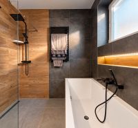 A bathroom in a family house with a shower, a bathtub, and tiles in a wooden decor.