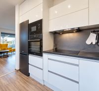 Family house with a kitchen and living room, wooden decor flooring, comfortable seating.