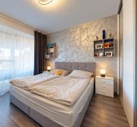 A bedroom with a soft headboard and wooden decor flooring in a family house.