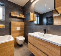 A bathroom with dark tiles and a wooden decor floor in a family house.