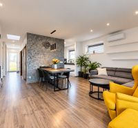 Living room in a family house with a wooden decor floor, a sofa, and a yellow armchair.
