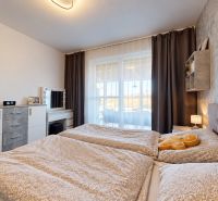 Bedroom in a family house with a comfortable bed, dresser, and decorative curtains.