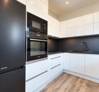 A kitchen in a family house with black appliances and a wooden decor floor.