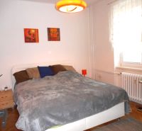 Bedroom in a 2-room apartment with a double bed, nightstands, and a wooden decor floor.