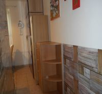 A narrow space in a 2-room apartment with wooden furniture and a tiled floor.