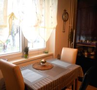 Dining area in a 2-room apartment, with a window and designer curtains, wooden decor.