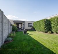 A garden of a family house in Oľdza with a lawn, a hedge, and a terrace for relaxation.
