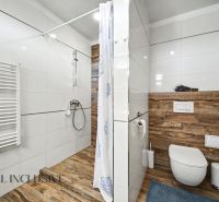 A bathroom in a family house with wood-patterned tiles and a shower enclosure.