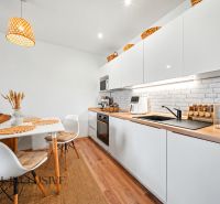 Kitchen with dining area, white cabinets, and wood-patterned flooring.