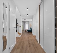 Interior of a family house with wood-patterned flooring, stairs, and modern lighting.