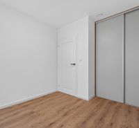 Interior of a family house with white walls, a wardrobe, and a floor with a wooden decor.