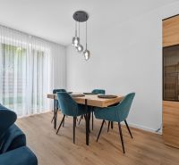 Dining area with a table, turquoise chairs, and a wood-patterned floor in a family house.