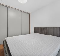 Bedroom in a family house with a bed, wardrobe, and wooden decor flooring.