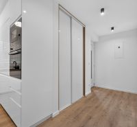 A hallway in a family house with a wooden-patterned floor and a white built-in wardrobe.
