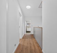 A hallway in a family house with a wooden decor floor and a light interior.