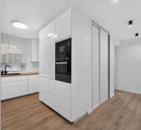 A kitchen with white cabinets, built-in appliances, and a wood-patterned floor in a family house.
