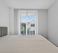 Bedroom in a family house with a bed and curtains, light walls and a window with a view.