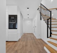 Interior of a family house with wood-patterned flooring, white furniture, and a staircase.