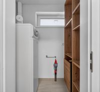 Laundry room in a family house with a washing machine, shelves, and storage space.