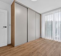 A bedroom in a family house with a large wardrobe and a floor with a wooden decor.