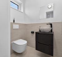 A bathroom in a family house with a toilet, sink, and black furniture.