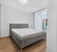 A bedroom in a family house with an upholstered bed and a floor with a wood decor.