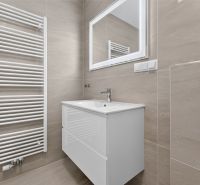 Bathroom in a family house with a sink, mirror, and ladder radiator.