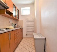Offices with a kitchenette, wooden decor, three trash bins, narrow window on the wall.