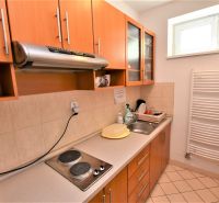 Kitchen unit with a sink and stove in the office, light ceramic floor, radiator.
