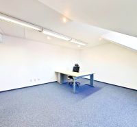 An office with air conditioning, a desk and a chair, white walls, slanted roof.