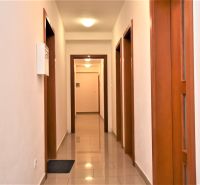 A hallway in an office with tiles and wooden door frames.