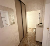 A hallway in a 3-room apartment with glossy tiles, a mirror, and a built-in wardrobe.