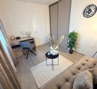 A room in a 3-room apartment with a wooden decor floor, a desk, and decorations.