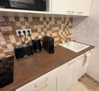 A kitchen in a 3-room apartment with a microwave, kettle, and coffee maker on the countertop.